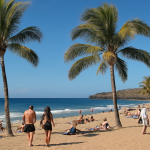 Sonniger Strand auf Teneriffa mit Palmen und Menschen.